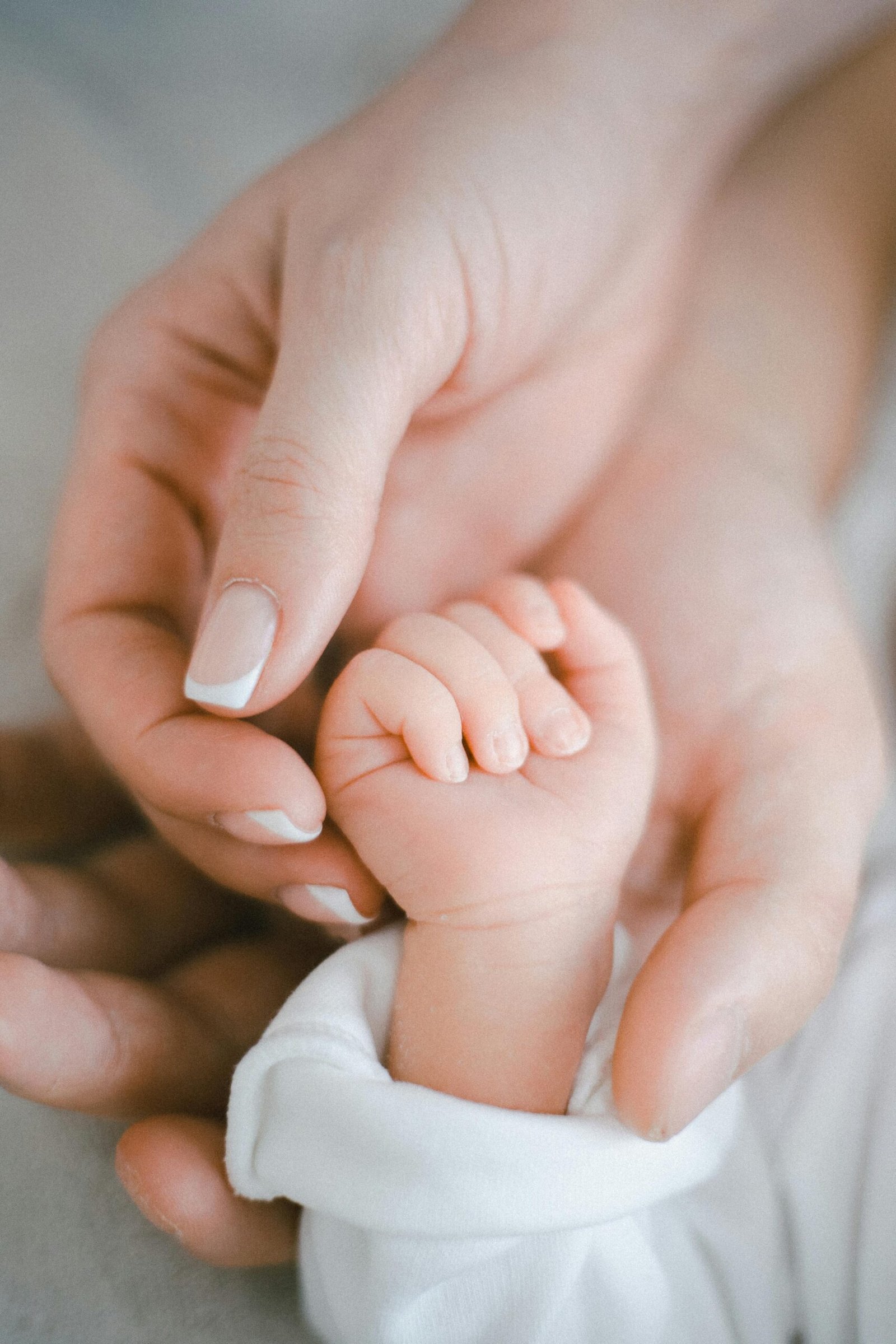 A close-up of a newborn baby gently holding their mother’s hand, symbolizing the tender connection and love shared in the early moments of life