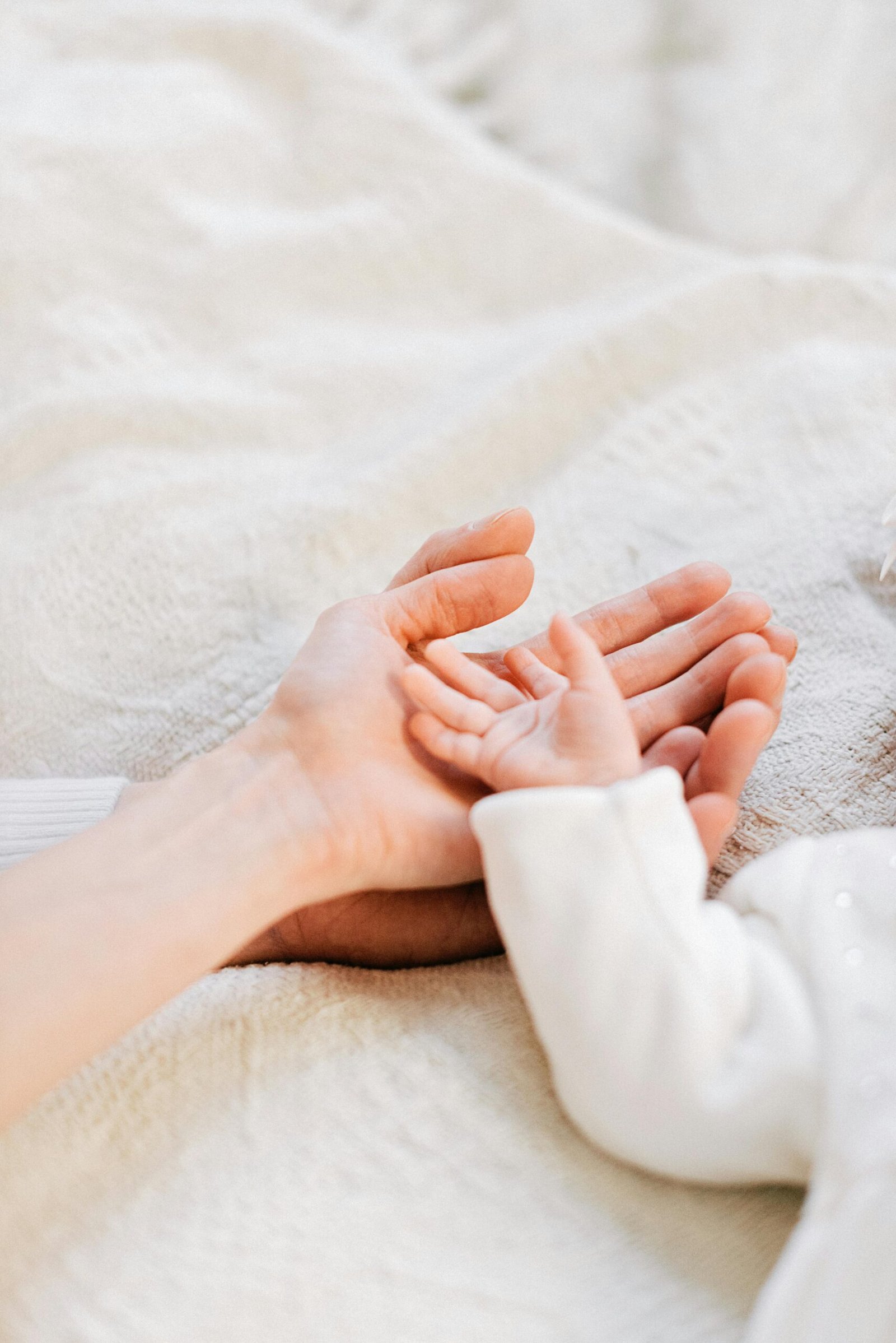 Baby's tiny hand resting gently on mother's hand, symbolizing the bond of motherhood.