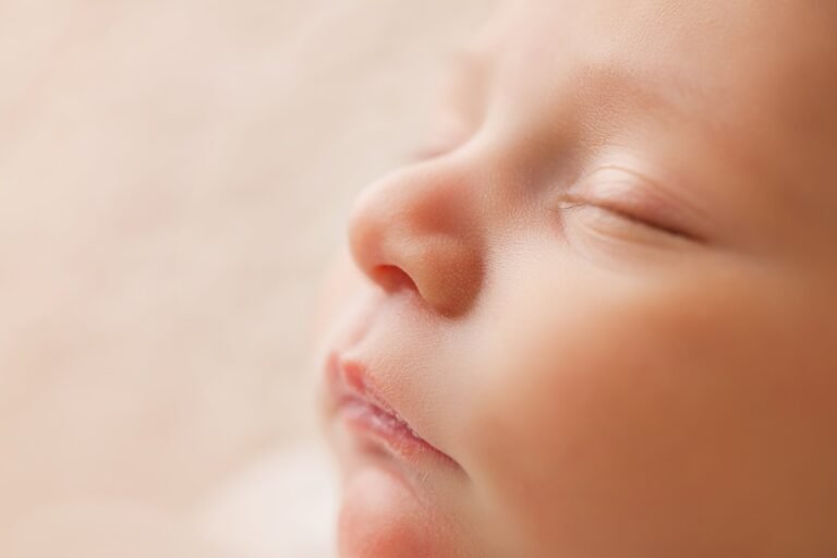 Close up of a newborn baby's face with eyes closed.