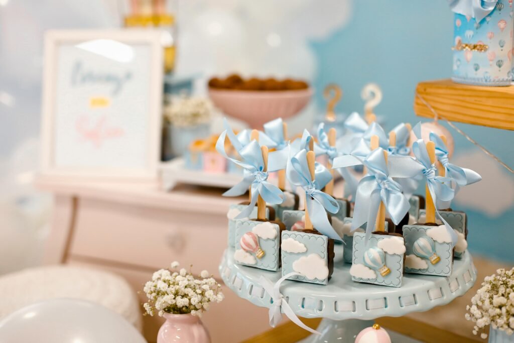 Elegant baby shower dessert table with blue-themed treats, decorated with bows and hot air balloon design