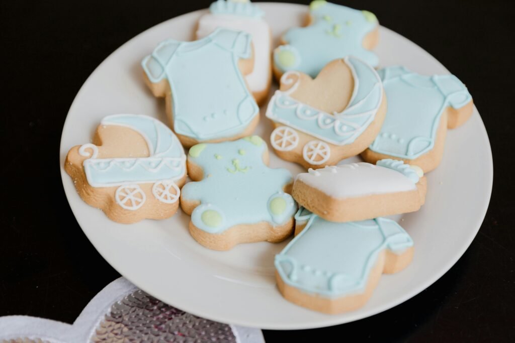 Light blue baby shower cookies shaped like onesies, prams, and teddy bears, perfect for a baby boy-themed celebration.