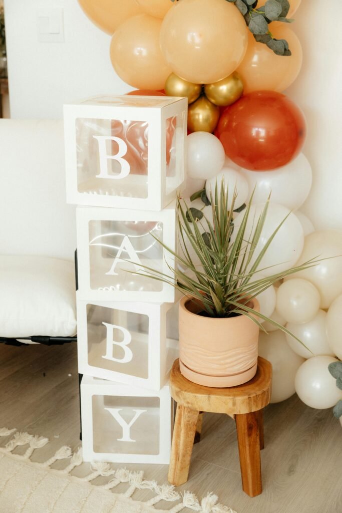 Minimalist baby shower decor with white letter blocks spelling 'BABY' and neutral-toned balloon arrangement, perfect for a simple and chic baby shower.